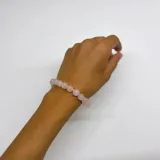 Pulsera elástica compuesta por cuentas esféricas de cuarzo rosa de 8 mm, unidas por nudos de hilo rosado.