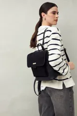 Mochila estructurada negra con frente en gamuza y cuerpo en símil cuero texturizado. Tiene asa superior y correas regulables.
