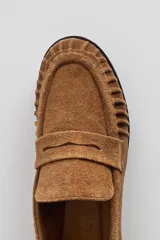 Mocasín de cuero marrón con textura croco y acabado brillante, de diseño clásico con detalle de antifaz en el empeine y costuras pespunteadas alrededor de la puntera.