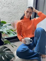 Sweater verde esmeralda de punto trenzado, con cuello alto y mangas largas.