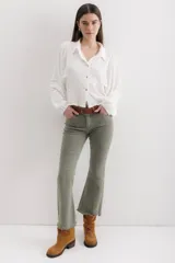 Pantalón de jean color marrón óxido, tiro medio, corte ajustado en muslos y ligeramente acampanado en la parte inferior (bootcut/flare), con bajo desflecado.