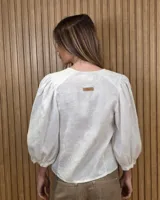 Camisa de cuello redondo y manga larga abullonada, con diseño a rayas en tonos rosado y blanco.