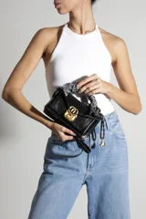 Mini bolso bandolera de cuero negro Schutz, con cierre de solapa frontal y herraje metálico dorado. Cuenta con manija superior decorada con un pañuelo estampado y correa larga ajustable para llevar al hombro o cruzada.
