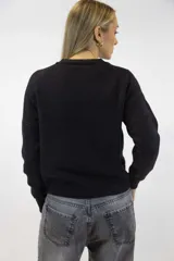 Buzo de tejido fino color beige con delicados destellos brillantes integrados en la trama. Presenta cuello redondo, mangas largas con corte raglán y terminaciones acanaladas en cuello, puños y cintura.