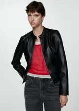 Chaqueta tipo biker de efecto piel en color negro, con diseño corto, cuello redondo abotonado, cierre frontal con cremallera y bolsillos laterales con cremallera.