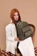 Mochila urbana de diseño funcional en color beige, confeccionada en tela impermeable. Cuenta con un compartimento principal amplio, un bolsillo secundario y un bolsillo frontal, todos con cierre. Incluye asa superior y correas ajustables para los hombros, con detalle de etiqueta de marca en el frente.