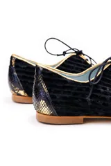 Zapatos tipo blucher de terciopelo de seda con diseño rayado en negro y oro. Presentan una abertura central ajustable con cordones, ribetes en contraste y detalles en piel con acabado de pitón multicolor en la puntera y el talón. Cuentan con suela de cuero e interior forrado en piel.