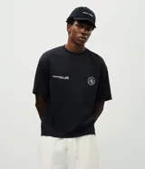 Remera de corte boxy con cuello redondo y manga corta, confeccionada en tejido de algodón y poliéster con acabado suave. Presenta estampado con lettering en el pecho y un diseño gráfico circular de mayor tamaño en la espalda.