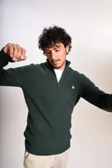 Sweater de punto acanalado en color verde oscuro, con cuello alto y cierre frontal parcial de un cuarto. Presenta puños y ruedo elásticos, con el logo de la marca bordado en el pecho.