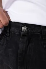 Jean de corte baggy y fit oversize, confeccionado en denim de algodón con lavado efecto gastado en color gris oscuro. Presenta costuras reforzadas en la zona de las rodillas y diseño de cinco bolsillos.