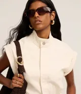 Mono largo de sarga color marrón, con cuello alto, cierre frontal con botones ocultos, sin mangas y bolsillos laterales. Incluye trabillas para cinturón.