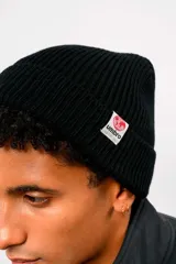 Gorro de lana tipo beanie de tejido acanalado, color blanco, con vuelta y pequeña etiqueta circular con el logo de Umbro en el lateral.