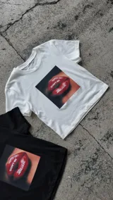 Remera negra corta con estampado frontal de labios rojos y la frase "Don't be jealous.", manga corta y cuello redondo.