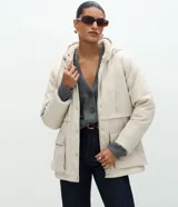Campera parka de Marfinno confeccionada en PU con textura gomosa, color beige. Cuenta con capucha, forro interior de peluche sintético, cierre frontal con solapa y botones a presión, y bolsillos delanteros grandes con solapa.