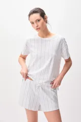 Pijama de algodón compuesto por una remera de manga corta con cuello redondo y un short con cordón ajustable en la cintura, ambos con diseño de rayas verticales formadas por pequeños motivos florales en tonos azules sobre fondo blanco.