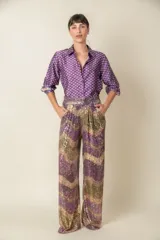 Pantalón italiano de corte palazzo, con cintura elastizada y forro de viscosa. Cubierto de lentejuelas con diseño de ondas en tonos violeta, dorado y verde.