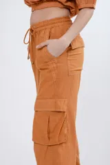 Pantalón cargo color naranja de lino, con cintura elastizada ajustable con cordón, bolsillos laterales con solapa y jareta en el ruedo.