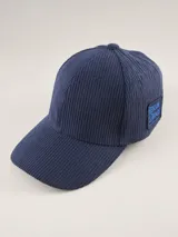 Gorra tipo baseball confeccionada en pana color azul marino, con parche rectangular lateral que incluye el logo de la marca Benson & Thomas.