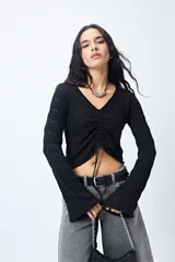 Top tejido negro con trama calada, escote en V, frunce central regulable y mangas acampanadas.