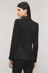 Blazer slim negro con tejido sastrero con lúrex, profundo escote en V, solapa tipo smoking de satén, un botón frontal, bolsillos ojal y tajo en la espalda.