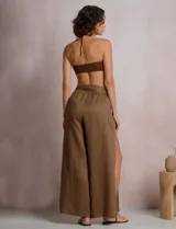 Pantalón palazzo de lino color azul, de tiro alto con cintura elastizada y cinto lazo incorporado con cuentas decorativas en las puntas. Presenta aberturas laterales pronunciadas en las piernas y corte amplio.