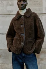 Chaqueta de cuello solapa y manga larga, con diseño de doble faz que combina tejido efecto ante y borreguillo. Cuenta con cierre frontal de botones y bolsillos delanteros.