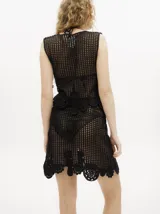 Conjunto de top y falda tejidos a crochet color rojo. El top es tipo chaleco con ajuste frontal con cordones y la falda es corta con pretina elástica y apliques de flores en el ruedo.