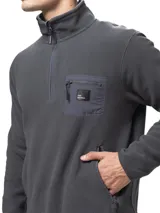 Buzo de polar gris oscuro con cuello alto y medio cierre frontal. Presenta un bolsillo en el pecho con cierre y detalles en nylon, además de bolsillos laterales con cierre.