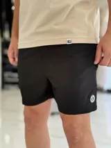 Short de baño gris liso, con diseño clásico y un pequeño parche circular con logo en la parte inferior de la pierna izquierda.