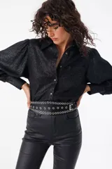 Cinturón negro de cuero con tres filas de ojales metálicos plateados y hebilla metálica.