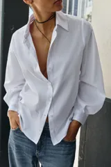 Camisa de algodón con diseño de rayas verticales sutiles, cuello solapa, manga larga con puños abotonados y cierre frontal con botones.
