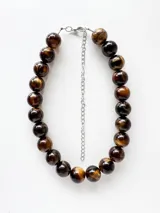 Collar de cuentas esféricas grandes con diseño marmolado en tonos marrones y beige, con cadena de extensión metálica plateada.
