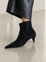 Bota de caña corta confeccionada en gamuza negra, con punta fina y taco fino tipo kitten heel.