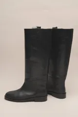 Bota de caña alta color marrón, confeccionada en cuero vacuno con forro y plantilla de cuero. Tiene suela de goma negra y un diseño de caña ancha.