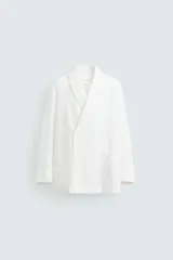 Blazer de corte relajado confeccionada en tejido de lino. Presenta cuello chal, manga larga, bolsillos de plastrón en la parte frontal y cierre cruzado con botones.