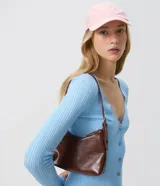 Cartera baguette pequea de poliuretano (cuero sinttico) color marrn, con cierre de cremallera superior, asa ajustable y herrajes metlicos.