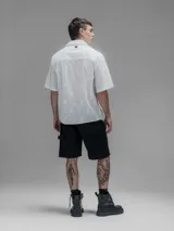 Camisa blanca de manga corta, con cuello abierto y calce oversize. Confeccionada en algodón bordado tipo broderie con diseño floral.