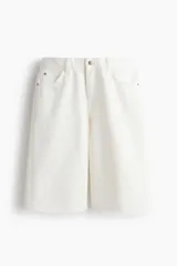 Bermuda de cinco bolsillos en denim de algodón rígido, corte baggy con cierre de botón y bajo deshilachado.
