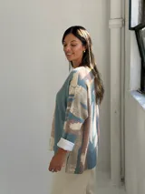 Sweater de punto con diseño abstracto de rayas verticales en tonos petróleo, beige y terracota. Presenta escote en V, corte holgado y mangas largas con puños vueltos.