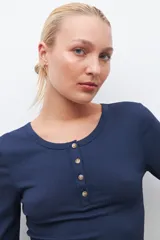 Remera verde de tejido canalé con cuello redondo y media manga. Tiene una abertura frontal con botones.