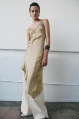 Vestido midi de satén con escote asimétrico y tirantes finos. Presenta una aplicación de encaje a tono en el escote y un bajo asimétrico.