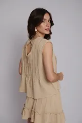 Blusa color beige con alforzas en la parte delantera y trasera, cuello redondo y mangas cortas con bordados artesanales.