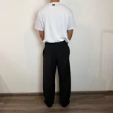 Pantalón sastrero color beige, de corte baggy, con pliegues en la cintura y bolsillos laterales.