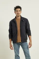 Campera estilo bomber color verde oscuro, con cierre metálico, dos bolsillos exteriores con cierre y un bolsillo interior.