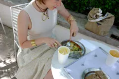 Collar con dije colgante de forma orgánica e irregular, acabado dorado, suspendido de un cordón negro de algodón natural.