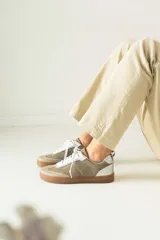 Championes de cuero color beige con detalles plateados y suela marrón.