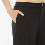 Pantalón negro de vestir, de corte ancho, con pinzas en la cintura y bolsillos laterales.