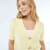 Sweater de punto color amarillo pastel, con cuello en V, manga corta y cierre frontal con botones decorativos en forma de estrella de mar.