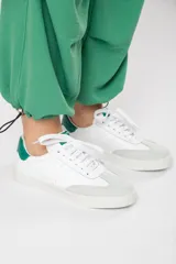 Zapatillas acordonadas de cuero color blanco con puntera de gamuza gris y detalles en verde.