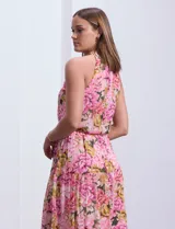 Vestido largo de gasa estampada con flores rosas, amarillas y verdes, marca Julia Jordan. Tiene escote halter, cintura elastizada con lazo de ajuste, abertura en la espalda con botones y forro interno a tono.